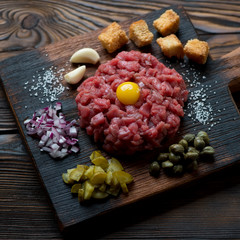 Close-up of beef steak tartare on a rustic wooden chopping board