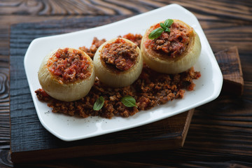Baked onions stuffed with minced meat on a glass plate, close-up