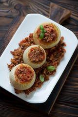 Glass plate with baked stuffed onions, above view, closeup