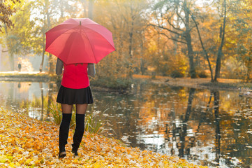 Junge Frau mit Regenschirm im herbstlichen Wald