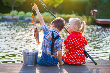 Little boy and girl fishing in a river. Sitting on a wood pontoon - obrazy, fototapety, plakaty