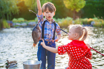 Little boy and girl fishing in a river. Sitting on a wood pontoon