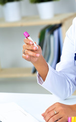 Woman researcher is surrounded by medical vials and flasks