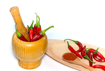 Red peppers in a wooden mortar and red peppers powder in a wooden spoon