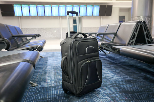 Black suitcase is left or lost at an airport hall.