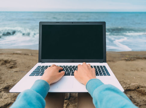 POV Image Of Working On Laptop On Beach