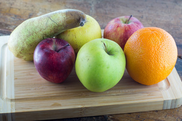 Frutta fresca di stagione, pere, mele, arance, primo piano su tagliere in legno
