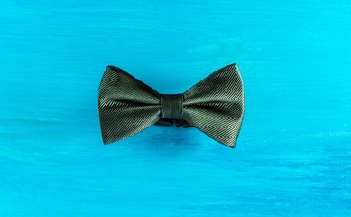 Black bow tie on turquoise wooden background