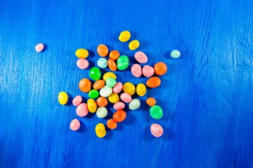 Multicoloured candies on blue wooden background