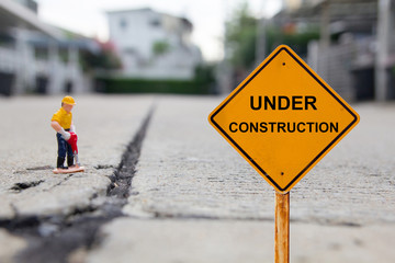 small figure of a man digging concrete street with Under Construction message.
