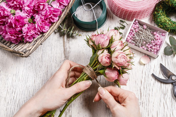 Woman making bouquet of pink roses.