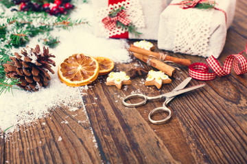 Handmade gift boxes near Christmas tree with cookies and spices.