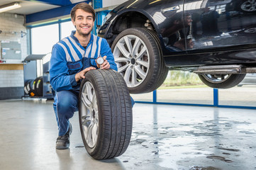 Fototapeta na wymiar Mechanic Pressing Gauge Into Tire Tread In Garage