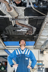 Fototapeta na wymiar Mechanic Examining Under The Car At Garage