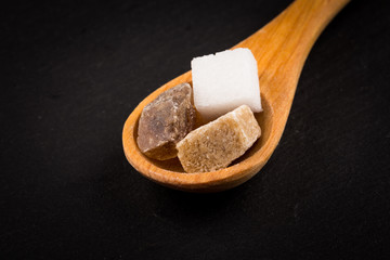 White refined and brown sugar in wooden spoon