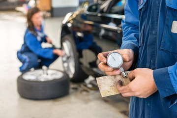 Midsection Of Mechanic Holding Analog Gauge In Garage