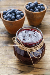 Jar of blueberry jam and bowls of blueberries