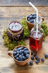 Jar of blueberry jam, bottle of juice and bowls of blueberries