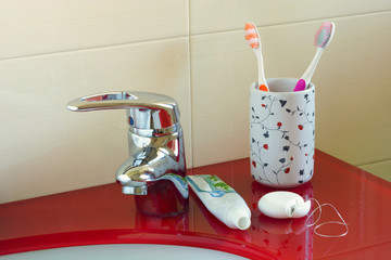 Toothbrushes, toothpaste and dental floss on the shelf of the bathroom sink