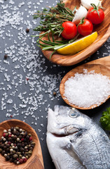 fresh raw dorado fish with spices and herbs on black background, top view