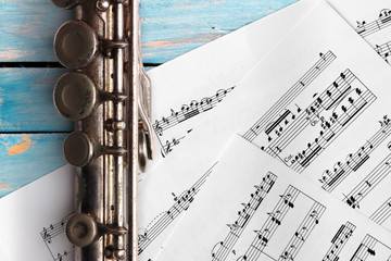 Obraz premium Old flute with sheet music on blue wooden boards