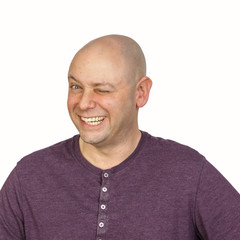 Big wink. Bald man in purple shirt in studio on white background give the viewer a big wink with...