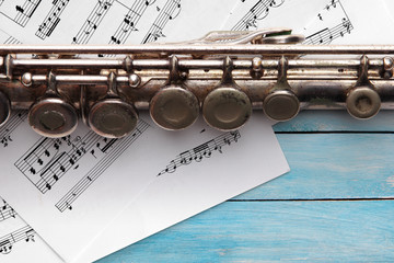 Obraz premium Old flute with sheet music on blue wooden boards
