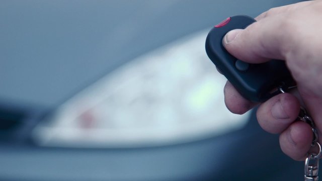 The man presses the button of the security alarm system in the car