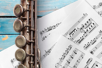 Obraz premium Old flute with sheet music on blue wooden boards