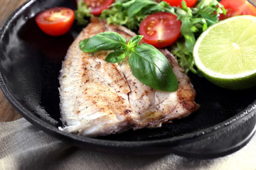 Dish of fish fillet with salad and lime on table close up