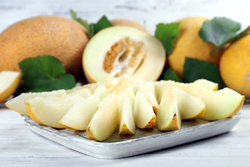 Ripe melons with green leaves on wooden table close up