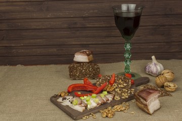 Preparing home-made snacks for the guests. Cutting board with smoked bacon and bread. Raw bacon. Whole grain bread
