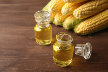 Fresh corn with bottles of oil on table close up