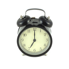 Alarm clock in black case shows 7 o'clock. Front view isolated on white closeup