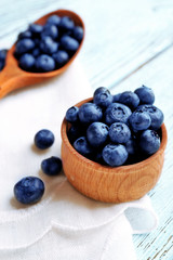 Fresh blueberries in spoon and bowl on table close up