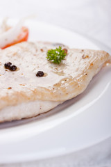 Roasted chicken filet with vegetables on a white plate. Closeup..