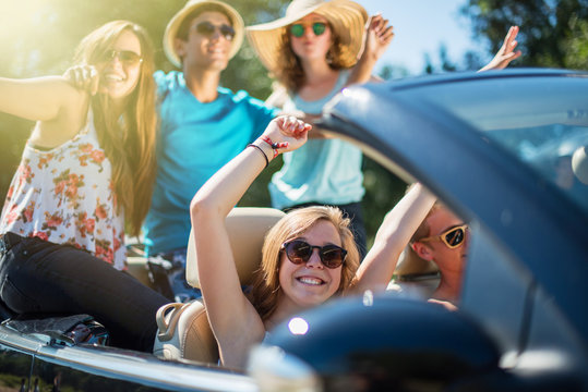 young people having fun in a black convertible by a sunny day