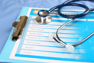 Medical stethoscope and clipboard on blue background