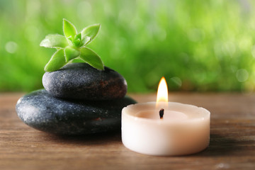 Spa stones and candle on wooden table closeup