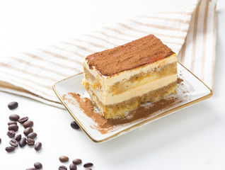 Tasty tiramisu cake with coffee beans on white