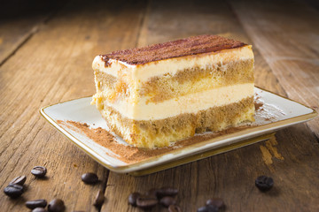 Tasty tiramisu cake with coffee beans on old wood