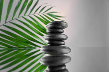 Spa stones and green palm branch  on grey background