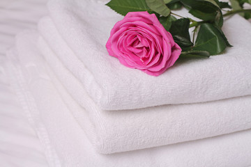Stack of white  and soft hotel towels decorated with rose flower. Perfect white laundry. Honeymoon concept