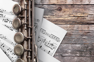 Old flute with sheet music on rusty wooden boards