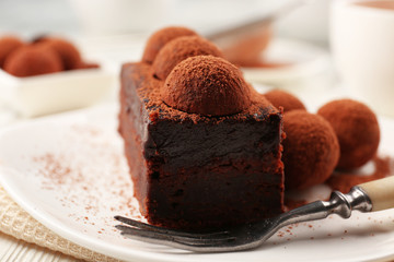 Slice of chocolate cake with a truffle on plate closeup