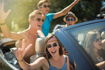 Young people having fun in the summer on a black convertible. 