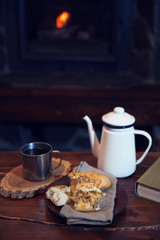 Teapot and mugs on vintage wooden table. Fireplace as background