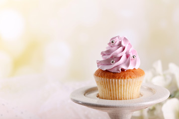 Tasty cupcake on stand, on light background