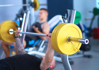Obraz premium Young man lifting the barbell in gym with instructor