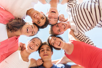 Under view of seven trendy teenagers arm in arm. 
